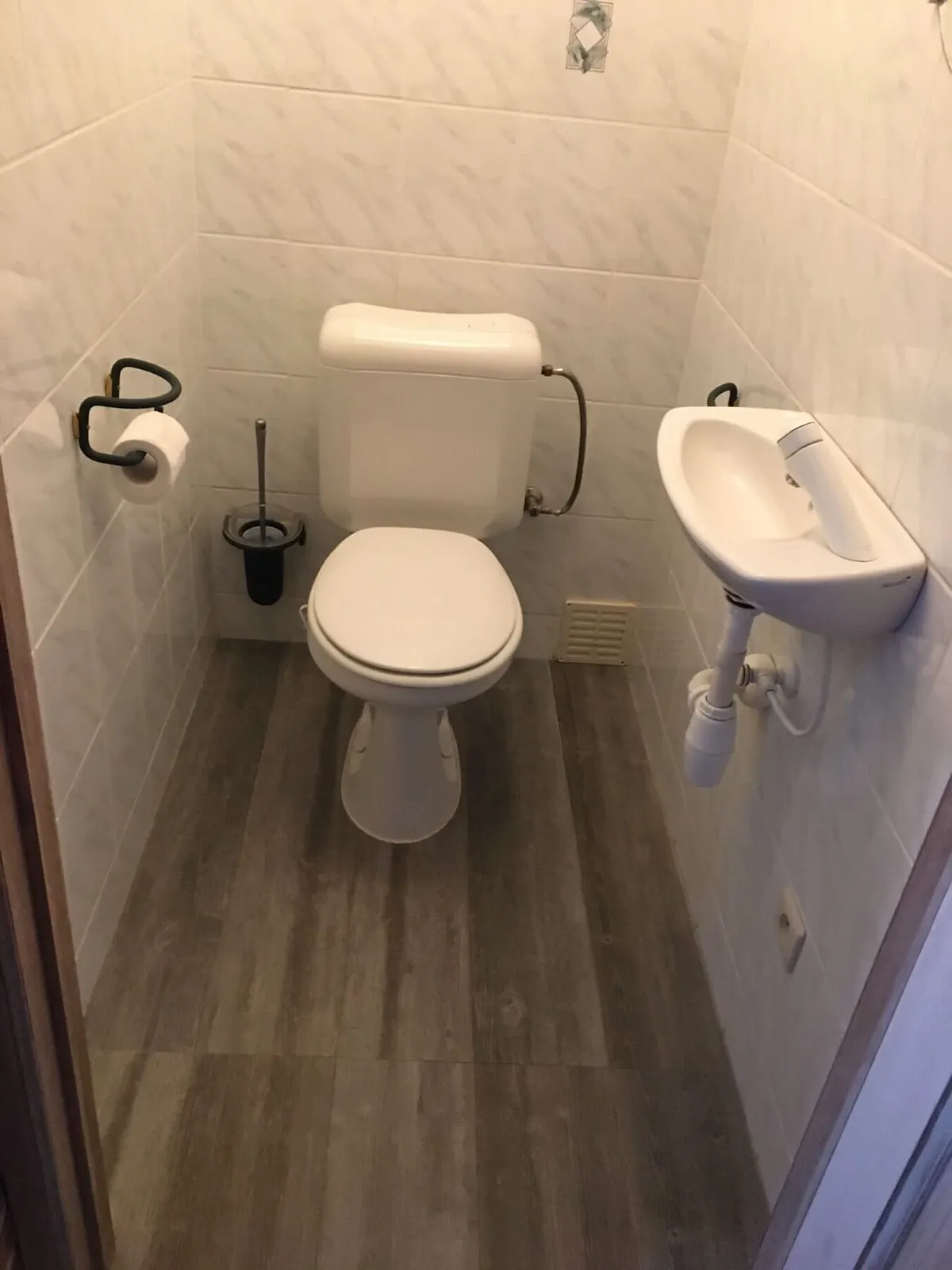 Oud toilet met witte tegels en fonteintje vóór de renovatie in Antwerpen