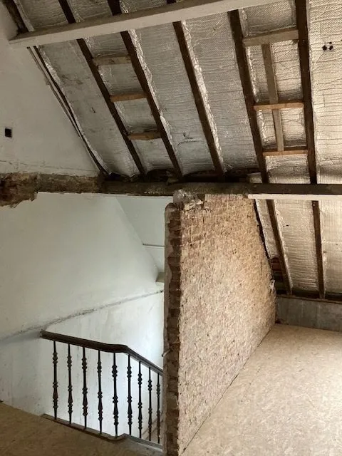 Trapgat en zolder met open dakgebinte vóór de renovatie in Antwerpen