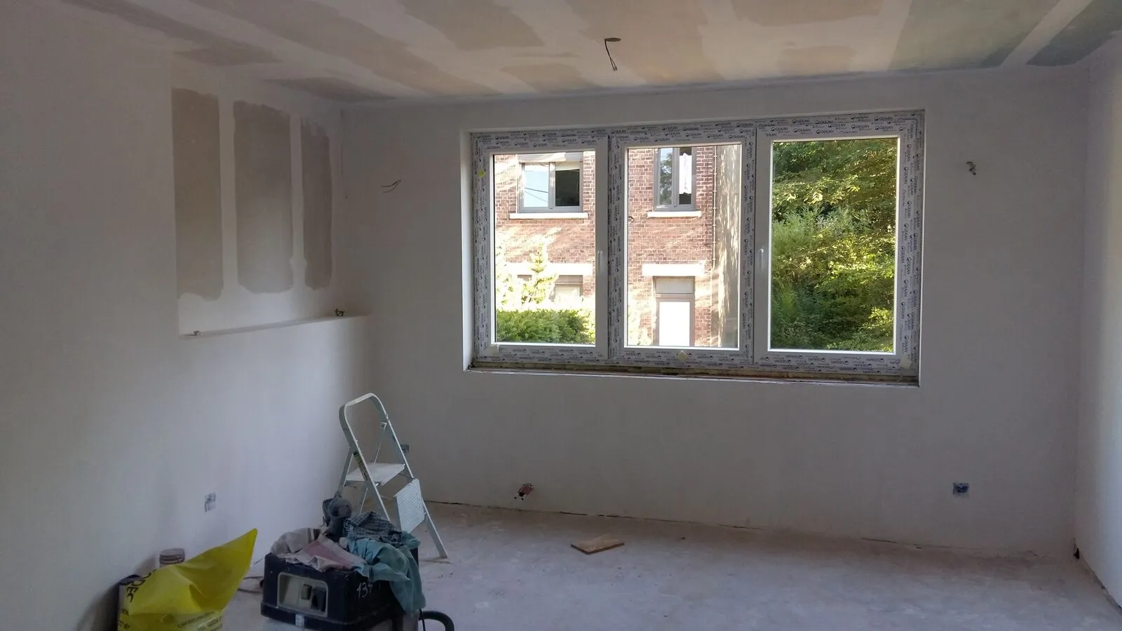 Living met kale, geschuurde muren vóór de renovatie in Rixensart