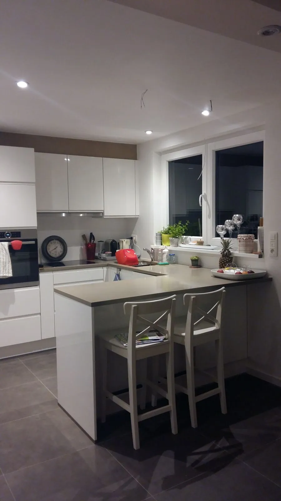 Open witte keuken met bar en krukken na de renovatie in Rixensart